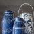 Set of blue and white hand-painted baskets, showcasing intricate patterns and golden accents, blending functionality with artisanal beauty.