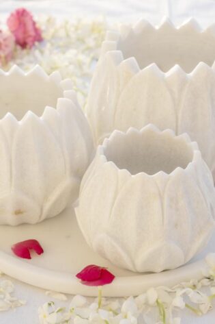 White marble Floret Candle Holders arranged on a tray amidst a sea of fragrant white petals and pops of red, embodying elegance for floor candle displays.