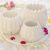 White marble Floret Candle Holders arranged on a tray amidst a sea of fragrant white petals and pops of red, embodying elegance for floor candle displays.