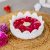 Elegant Ooze Candle Floater in white with vibrant red rose petals and a lit candle, set on a natural jute table mat, perfect for creating a peaceful ambiance.