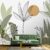 Contemporary Floral Leaves wallpaper featuring stylized plant illustrations in muted tones, creating a serene and stylish backdrop for a green velvet sofa.